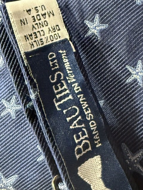 The Beau Ties Ltd label on a navy silk bow tie printed with starfish, reading hand sewn in Vermont