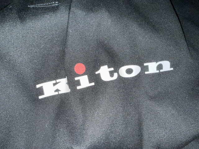 The Kiton label stitched into black cloth, with the red dot of the house logo