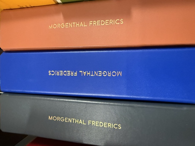 A row of Morgenthal Frederics eyewear cases in slate, cobalt and terracotta