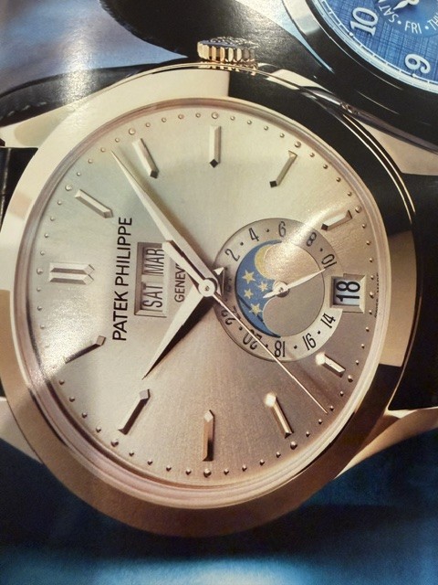 A Patek Philippe annual calendar wristwatch with a silvered dial, day and month apertures, date window, and a moon phase display.