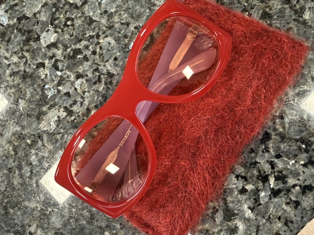 A pair of bold red acetate optical frames from Selima Optique on a granite counter