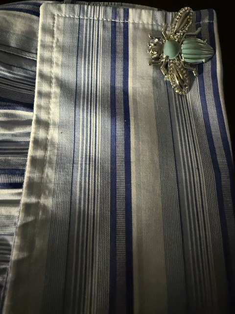 A blue and white striped Turnbull and Asser shirt cuff fastened with a jewelled insect cufflink